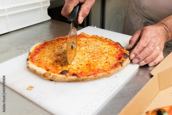 Obraz The chef cuts a hot 4-cheese pizza just out of the hot oven