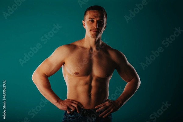 Obraz Happy, fit, male sports person posing on turquoise background in studio with slight smile on his face