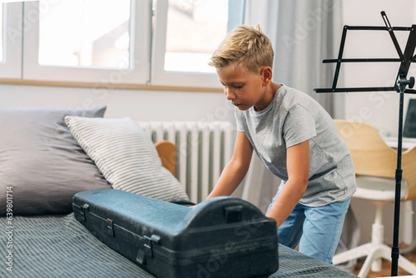 Obraz A boy is opening his instrument case.