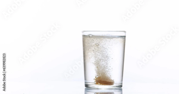 Obraz Tablets Falling and Dissolving into a Glass of Water against White Background