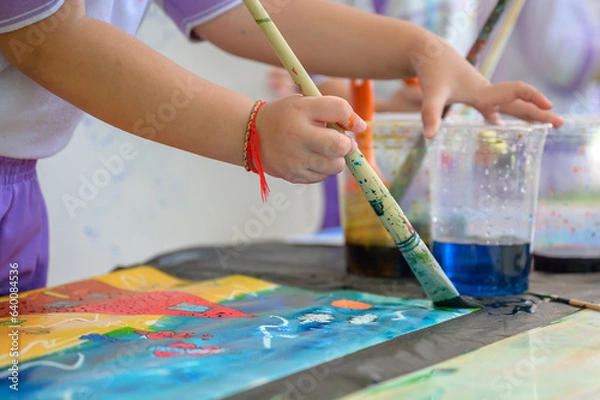 Fototapeta Children draw and paint water or crayons on the colorful drawing paper of their own creativity in the kindergarten class at the school.