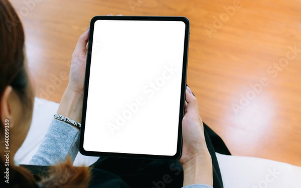 Obraz Woman holding and using tablet at home, blank screen tablet computer for copy space advertising text.