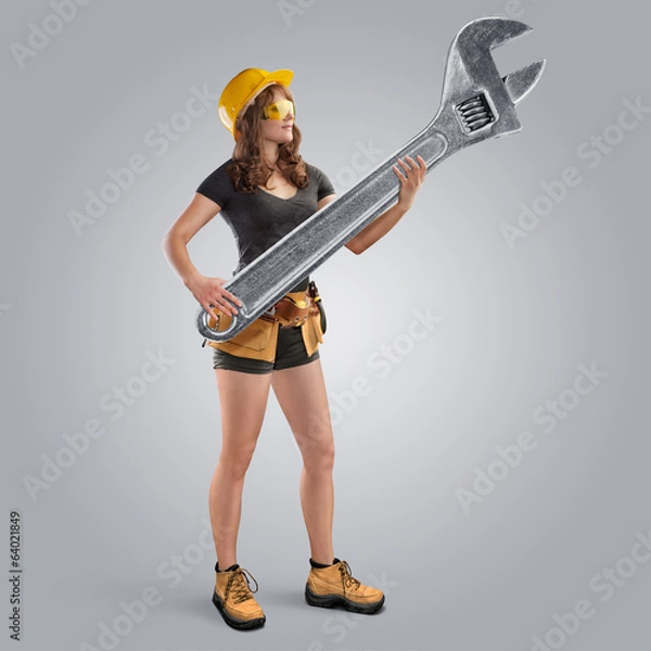 Obraz worker girl in a helmet holding a wrench