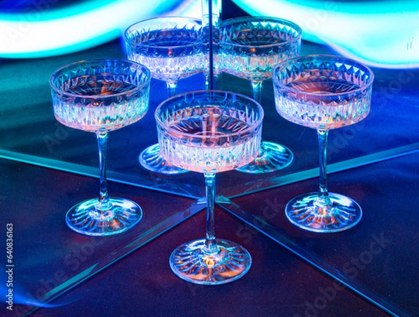 Obraz A glass of wine reflected in mirrors and illuminated by colored light