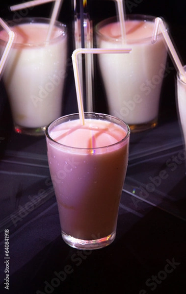 Obraz glasses with a milkshake reflected in mirrors and illuminated by colored light