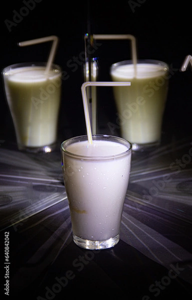 Obraz glasses with a milkshake reflected in mirrors and illuminated by colored light