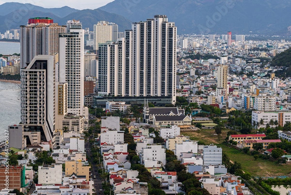 Fototapeta Nha Trang from the drone. In the background, a view of the city and skyscrapers. Between the buildings, a Catholic church and white houses. Vietnam