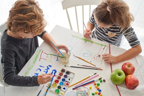 Fototapeta Children drawing on paper sitting at table