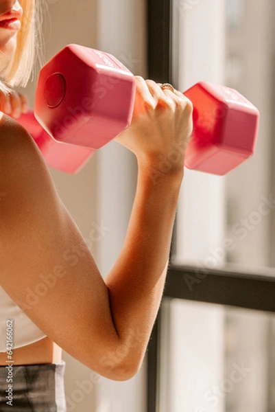 Fototapeta Unrecognizable beautiful young fit caucasian woman exercising with pink dumbbells indoors