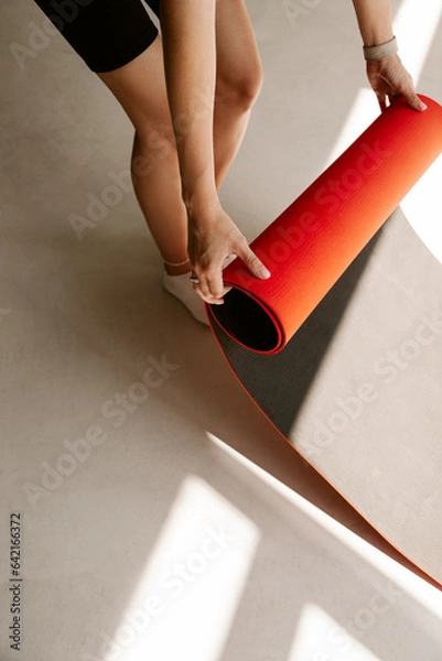 Fototapeta Crop image of a fit caucasian woman unrolling yoga mat