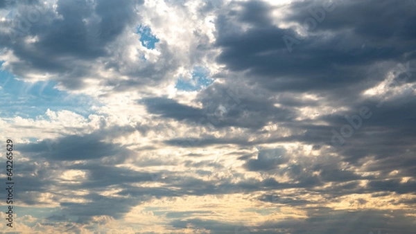 Obraz sunshine hide behind white and dark clouds on blue sky 