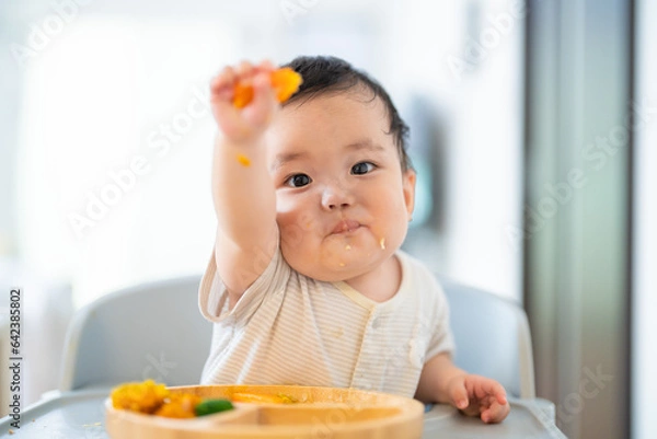 Fototapeta 離乳食後期でをつかみ食べをしてご機嫌な生後9か月の赤ちゃん