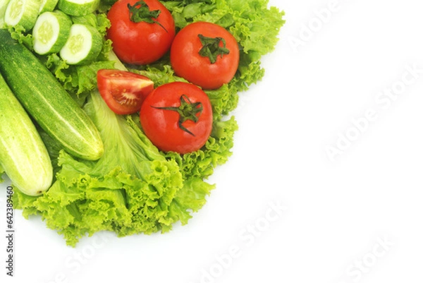 Fototapeta Cucumbers and tomatoes on salad leaves background isolated on white. Copy space for text.