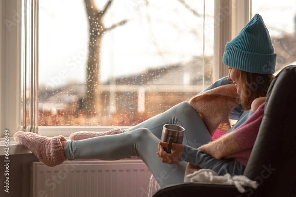 Obraz Beautiful woman drinking coffee or tea from a mug over autumn or winter scenery winter
