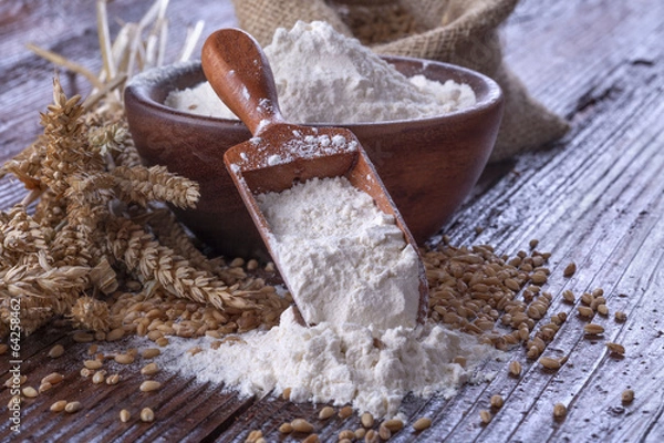 Obraz Shovel flour with wheat in background on wooden table