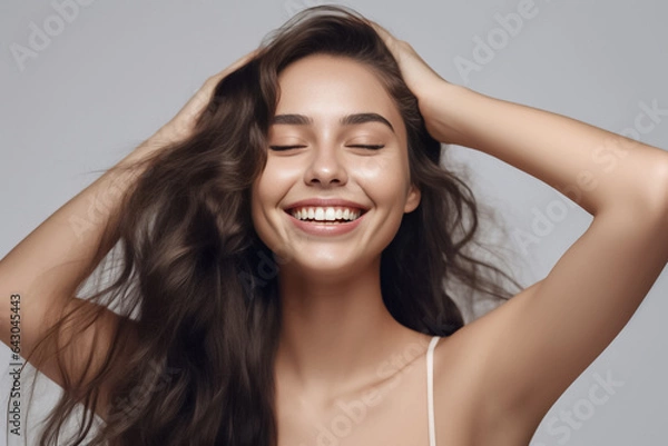 Obraz Charming Asian teenager with wavy long hair blowing in the breeze exudes positivity with a bright smile on a solid background. Generative AI.