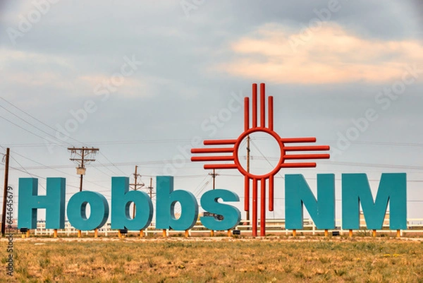 Fototapeta  City entrance sign with large turquoise colored letters and large Zia sign