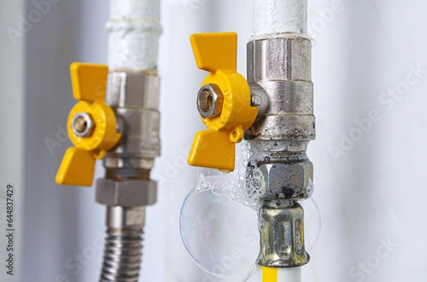 Fototapeta Gas leak at home kitchen. Inflating bubbles of soap mixture applied to the threaded joint on the gas flexible pipe indicate a gas leak. Preventing a gas explosion disaster.