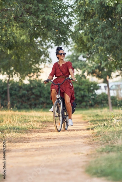 Obraz Ethnic woman riding bicycle and looking away