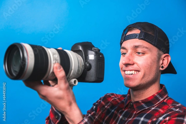 Fototapeta Happy photographer taking pictures checking his camera settings in a studio shooting as content creator