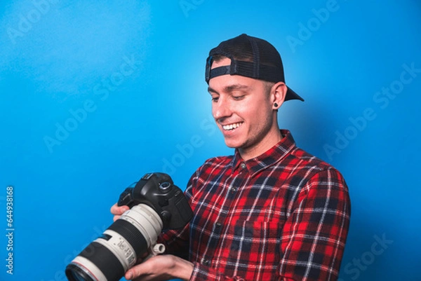 Fototapeta Happy photographer taking pictures checking his camera settings in a studio shooting as content creator