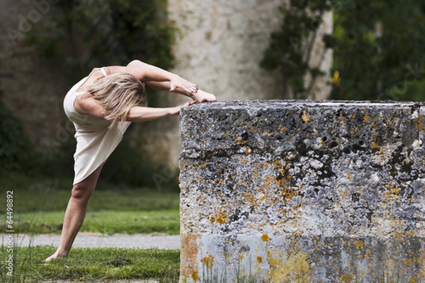 Obraz Assouplissements d'une danseuse blonde contre un muret.