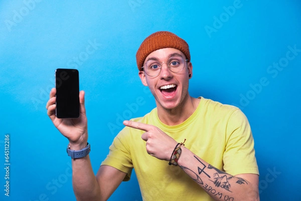 Fototapeta Happy young man showing smartphone with empty screen, mockup for mobile app or website design