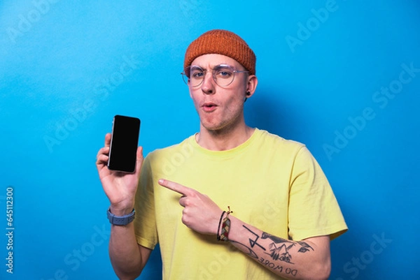 Fototapeta Happy young man showing smartphone with empty screen, mockup for mobile app or website design