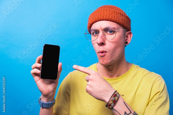 Fototapeta Shocked young man showing smartphone with empty screen, mockup for mobile app or website design