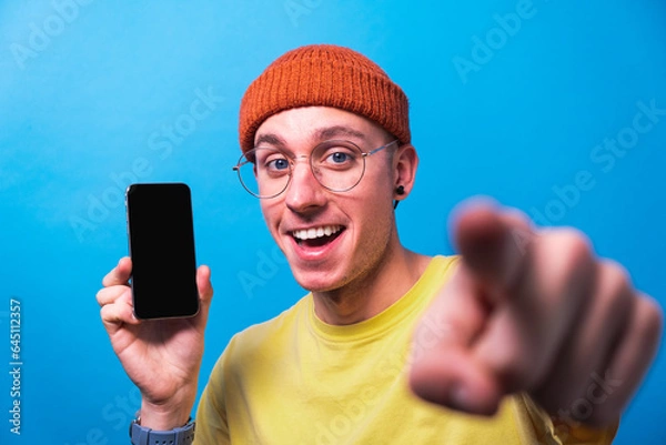 Fototapeta Young smiling man showing smartphone with empty screen, mockup for mobile app or website design