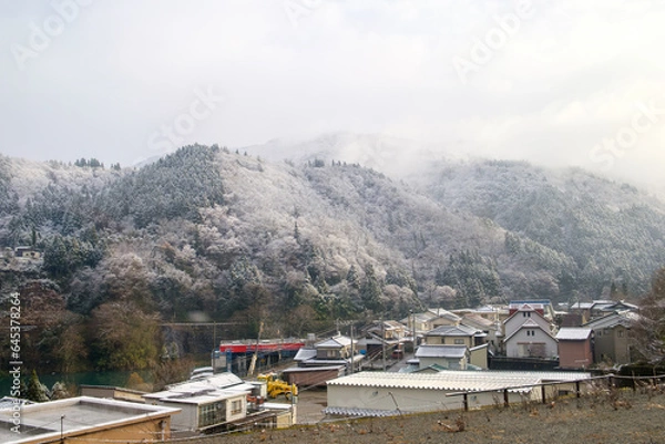 Fototapeta a rural village in Japan during the winter season. This picturesque scene showcases the village nestled among towering snow-capped mountains, creating a breathtaking backdrop of natural splendor.
