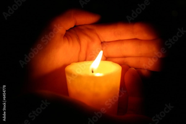 Fototapeta hands keeps burninging candle in the dark