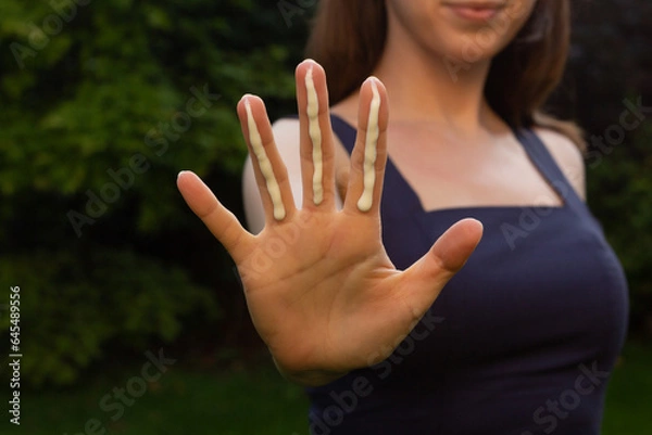 Fototapeta A woman applying the correct amount of sunscreen for face and neck (three finger lengths).