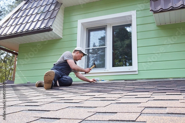 Obraz A worker greases the roof of the terrace with mastic.