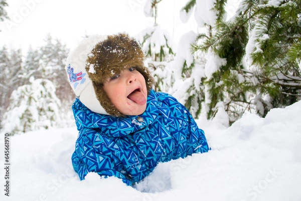Fototapeta Child play in the snowy forest in winter