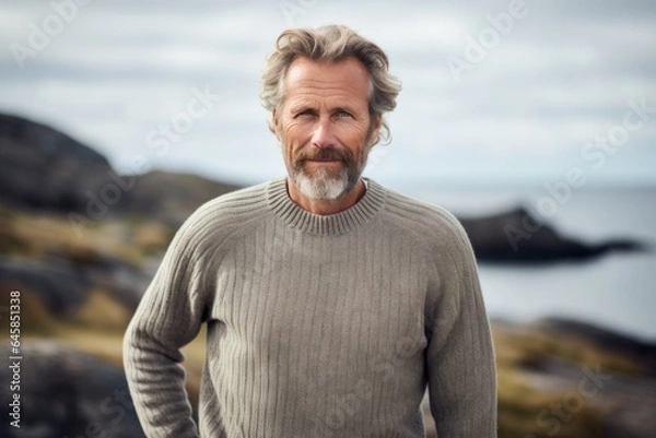 Obraz Portrait photography of a Swedish man in his 50s wearing a cozy sweater against a beach background