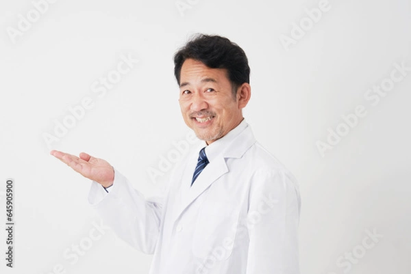Fototapeta 左側を手の平で指す中年の医師　白背景