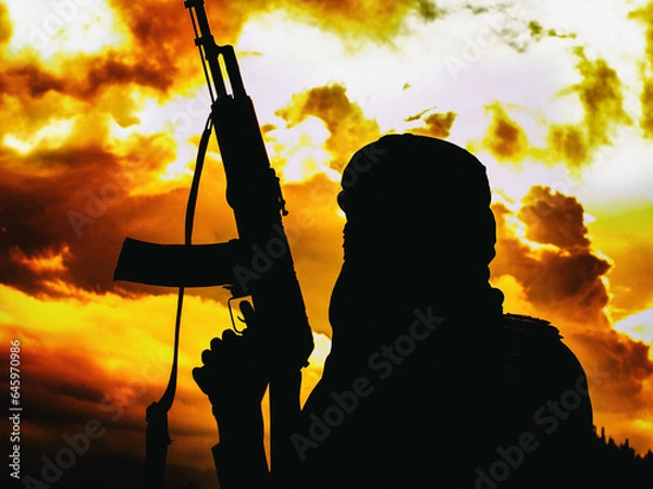 Obraz Muslim militant with rifle in the desert on sunset with AK rifle