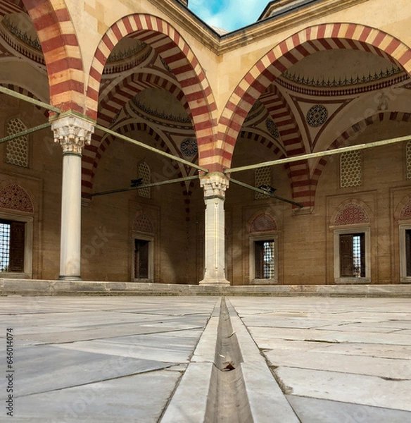 Obraz In terms of perspective, the stone arched domed mosque in the marble courtyard, shot from the ground and in focus, offers an aesthetic and historical view.