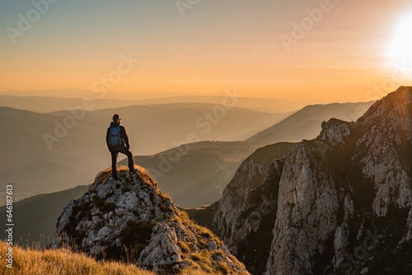 Fototapeta A man who hikers enjoys a break look at the top of the mountain at sunset adventure travel.