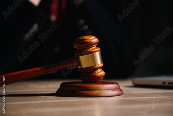 Fototapeta Justice and law concept.Male judge in a courtroom with the gavel, working with, computer and docking keyboard, eyeglasses, on table in morning light