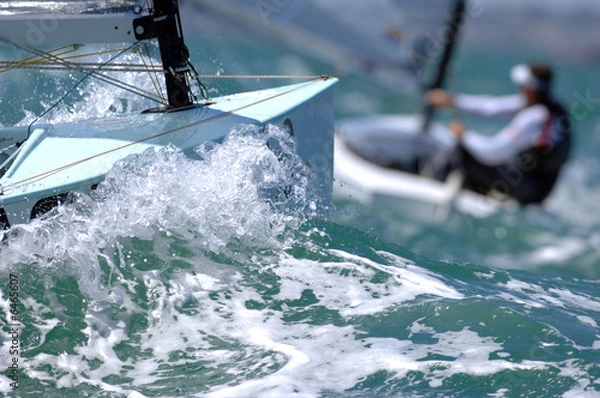 Fototapeta Sailors splash through the waves during a regatta.