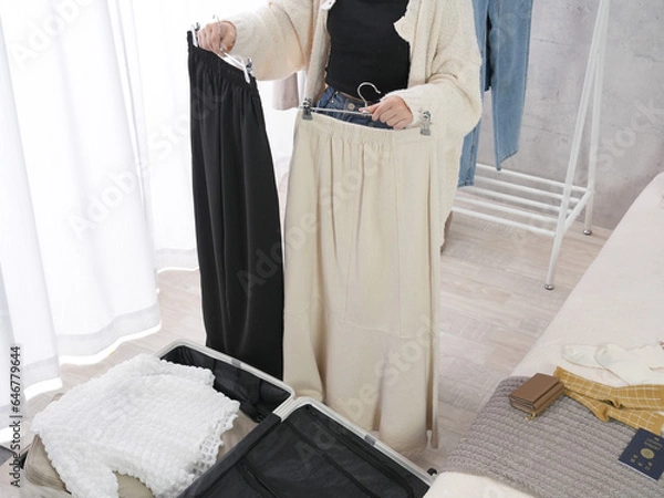 Fototapeta 旅行の服を旅行鞄に詰める女性