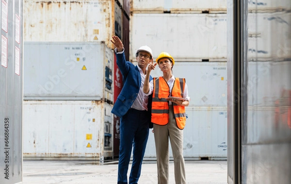 Fototapeta Workers having discussion against cargo containers