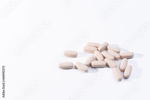 Obraz Pile of speckled, oblong, tablets on a white background.  Glucosamine chondroitin dietary supplements on a white background.