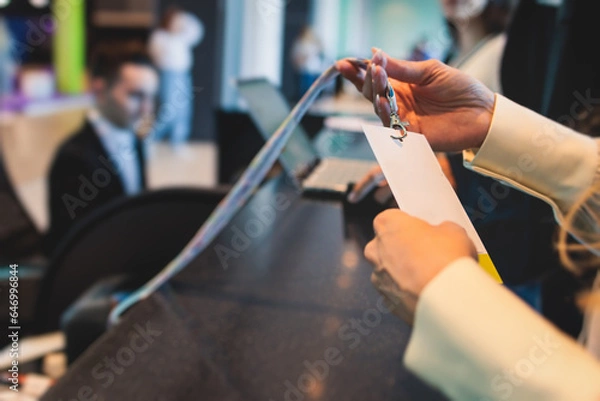 Fototapeta Process of checking in on a conference congress forum event, registration desk table, visitors and attendees receiving a name badge and entrance wristband bracelet and register electronic ticket
