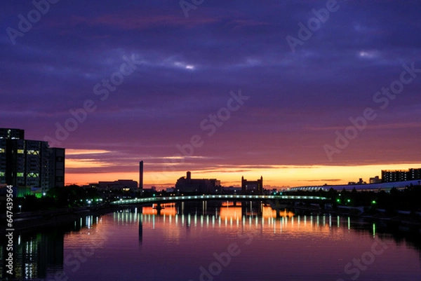 Fototapeta 夜明け前、東の空と水面がオレンジ色に染まりビルがシルエットで浮かぶ。神戸市内から芦屋方面をのぞむ。