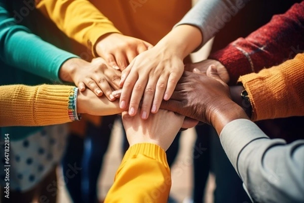 Obraz A group of people joining their hands together in unity and support. This image can be used to represent teamwork, cooperation, friendship, or community engagement.