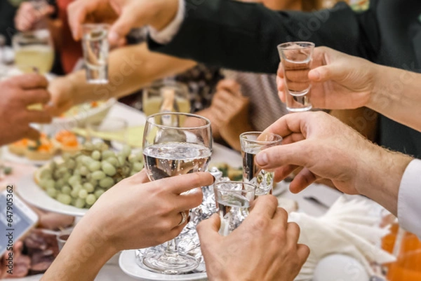 Obraz The hands of a group of people clink glasses and glasses of alcohol at a feast in a restaurant