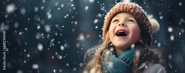 Fototapeta Magic of a child's wonder as they catch snowflakes on their tongue during the first snowfall of the season